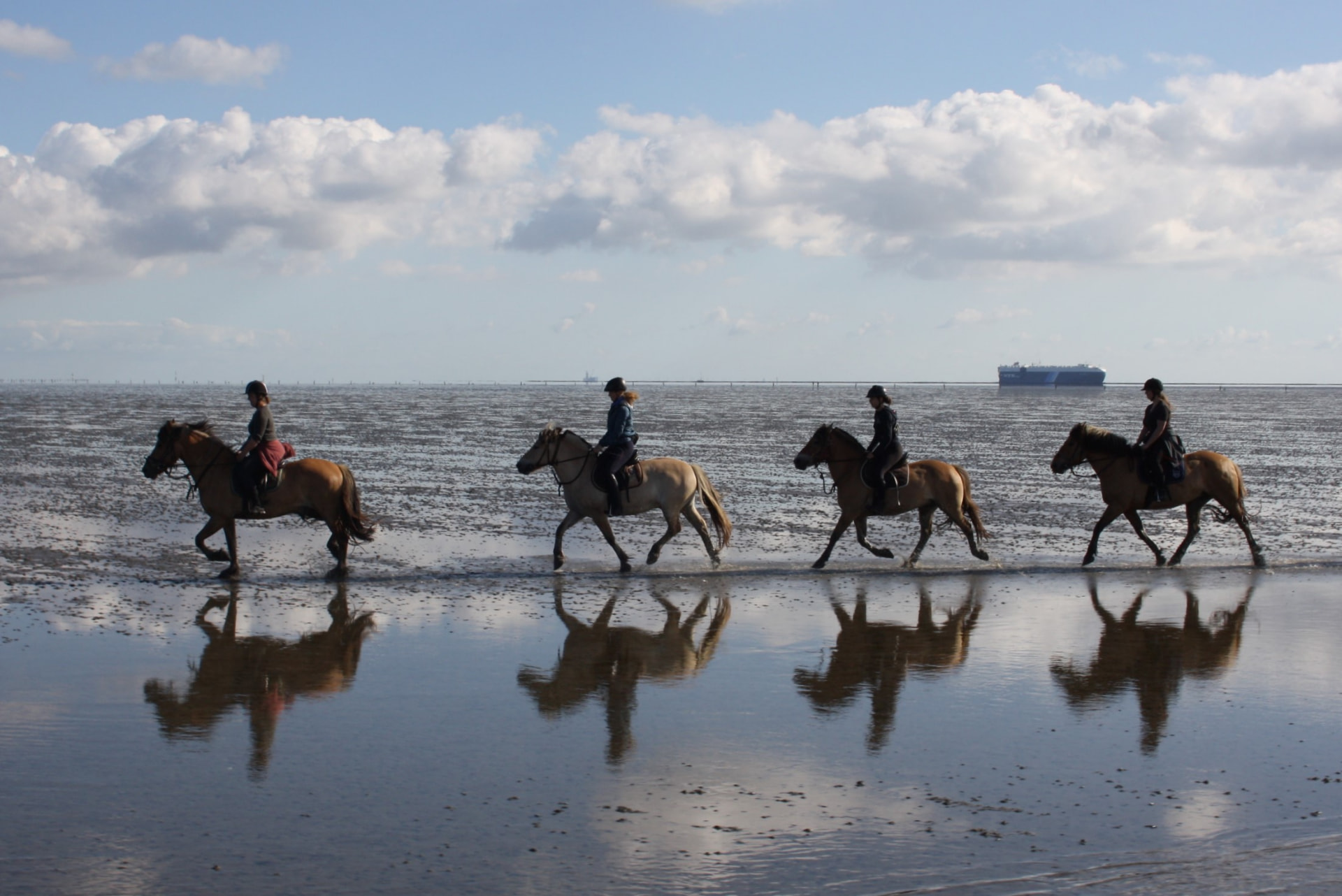 Reiter wandern durch das flache Wattenmeer vor Cuxhaven