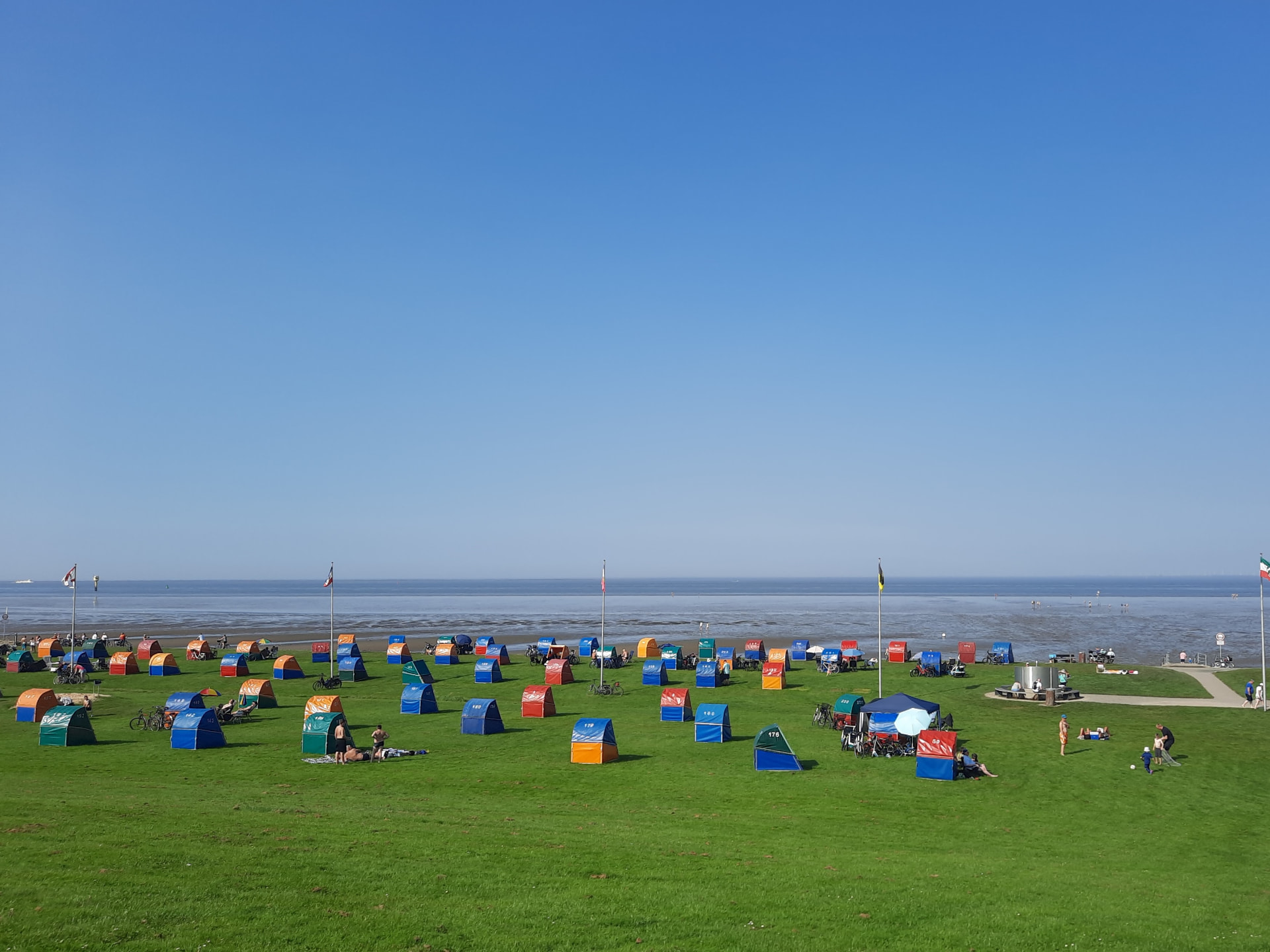 Bunter Strand am grünen Deichvorland bei Otterndorf mit Strandzelt, Watt und weiter Wasserfläche